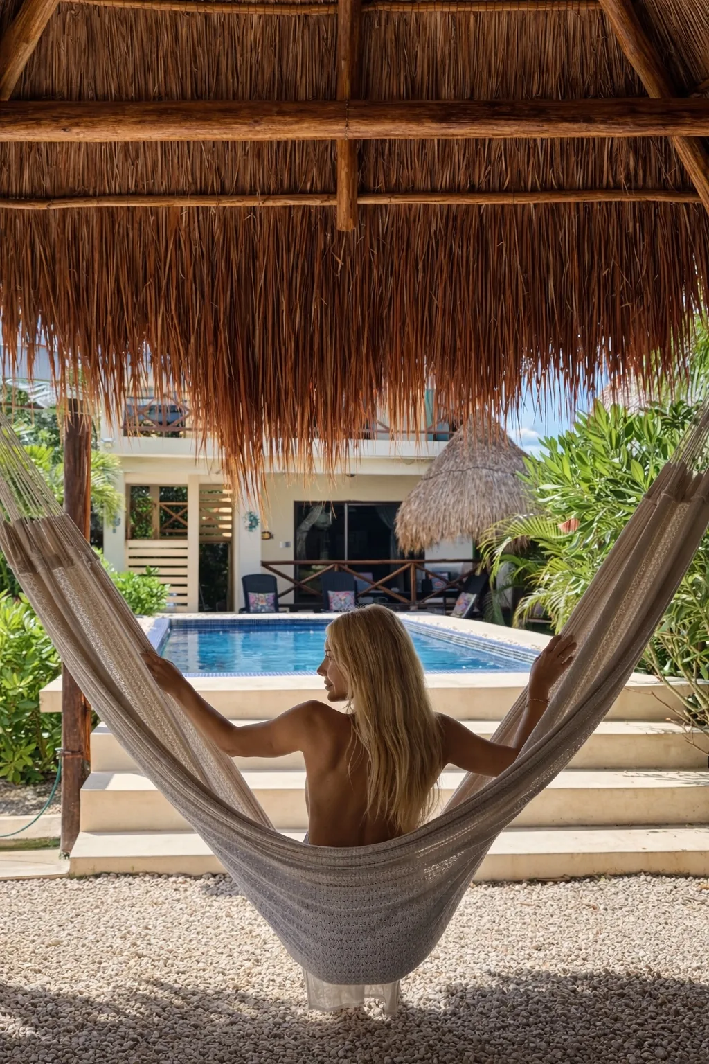 Guest in a hammock under the palapa beside the swimming pool