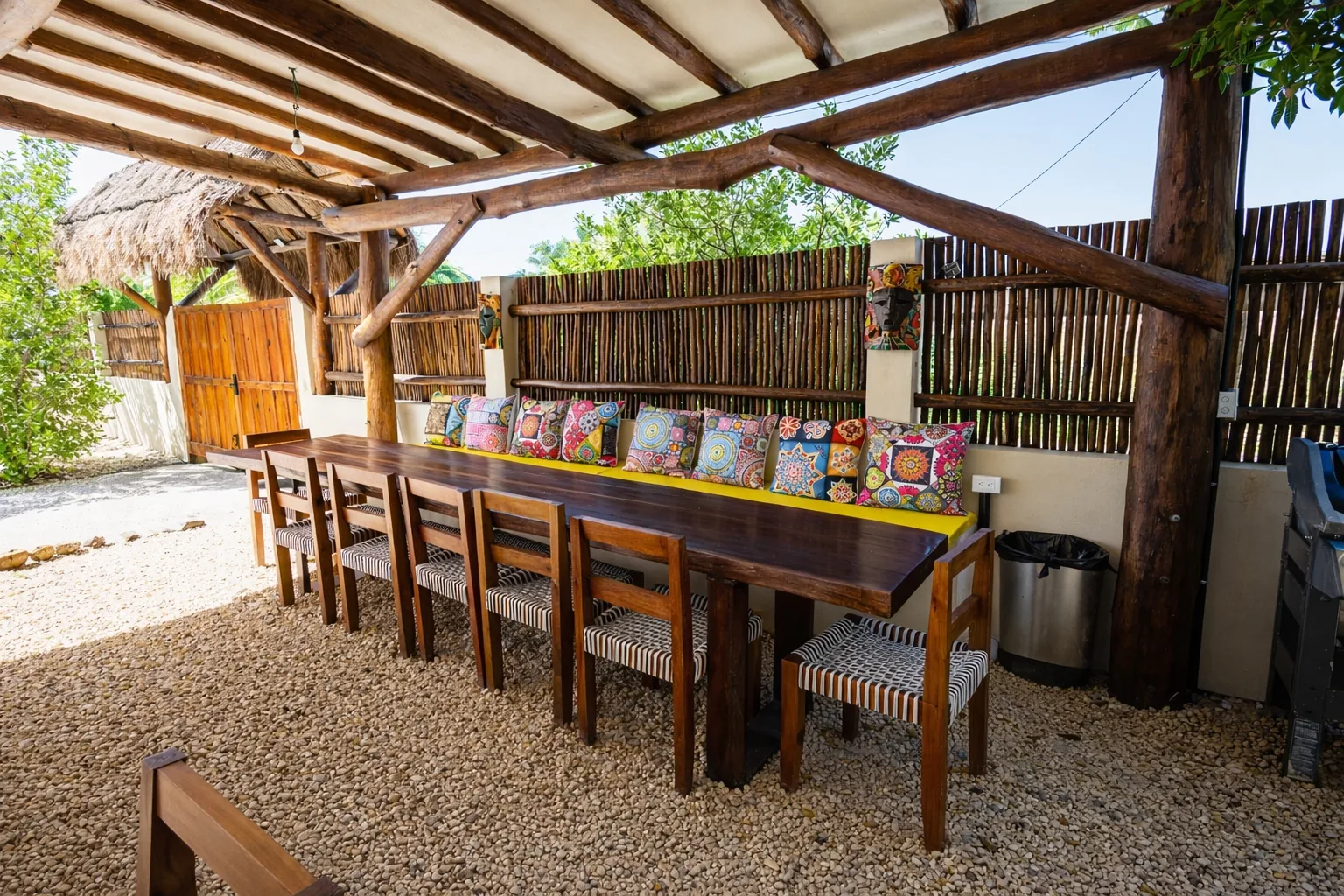 Palapa dining terrace with a long table and embroidered cushions