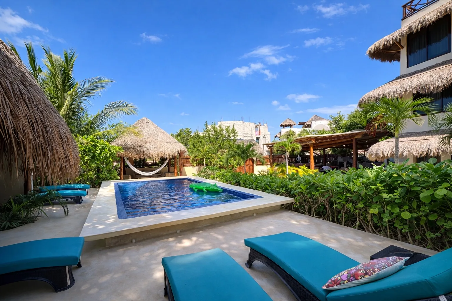 Swimming pool with turquoise loungers and thatched palapas at Atenea Holbox
