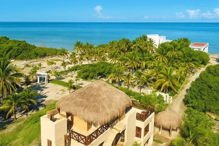 Aerial view over Atenea Holbox rooftop toward the palms and sea of Punta Coco