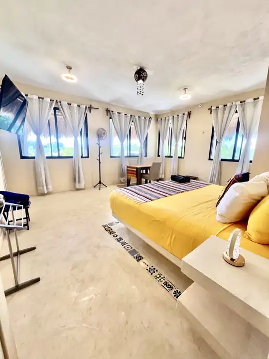 Coco Beach Room with king bed, yellow linens and wraparound windows with sea light