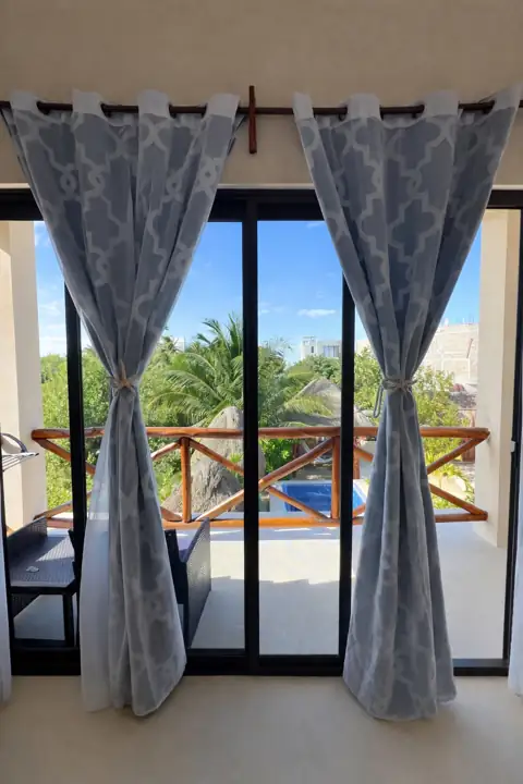 Frida Room balcony doorway opening to the pool and palapa garden at Atenea Holbox