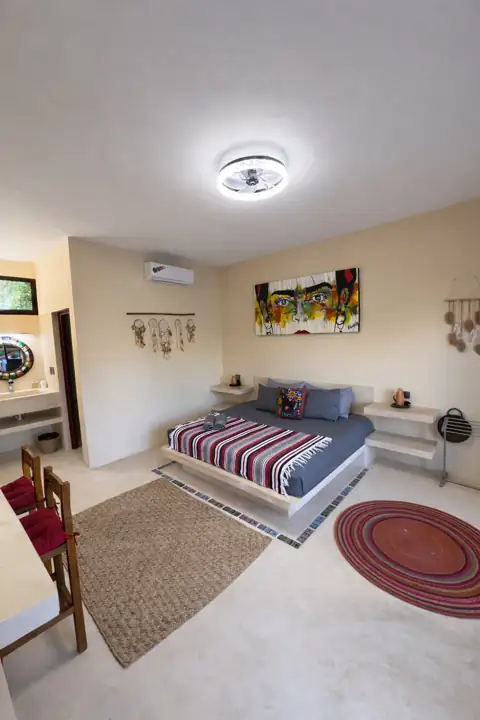 Frida Room with grey platform bed, colourful Mexican artwork and round woven rug