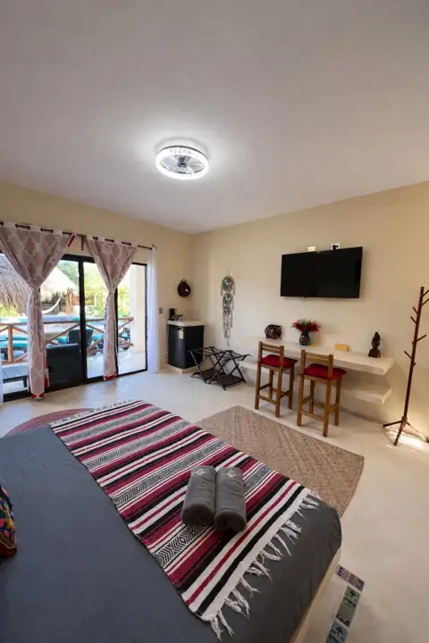 Frida Room with striped throw, dining nook and balcony doors to the pool