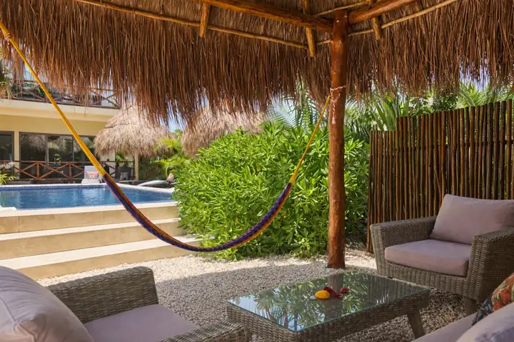 Palapa lounge with hammock and wicker sofas beside the pool at Atenea Holbox