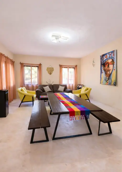 Living room with communal dining table and Mexican art in the main building