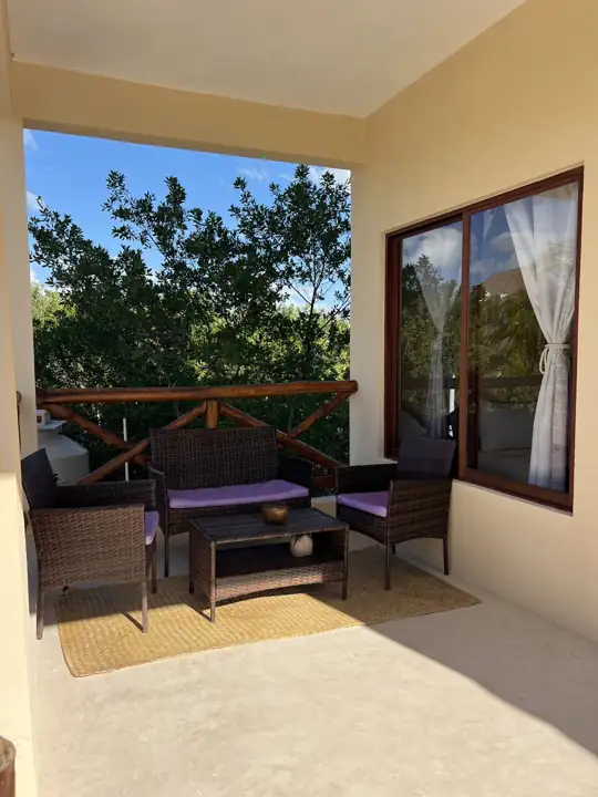 Private balcony with wicker seating and garden views at Atenea Holbox