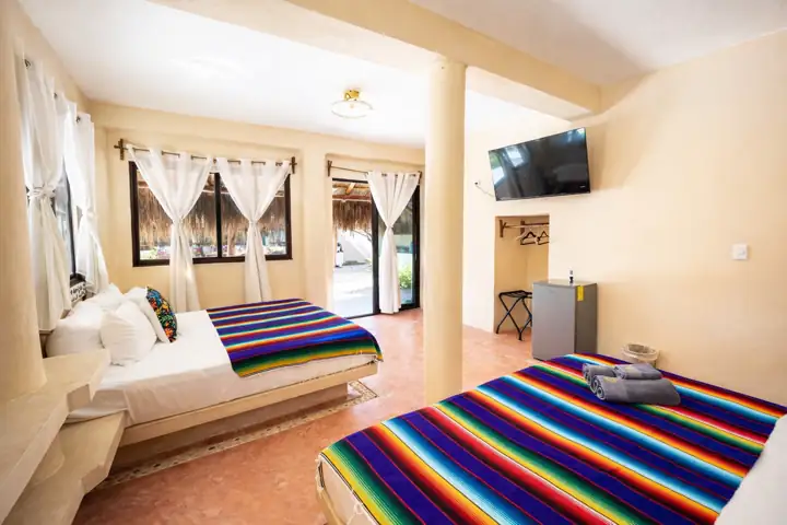 Luma Suite with one king and one queen bed and windows onto the palapa garden