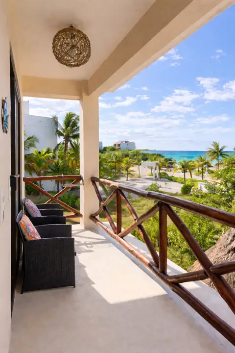 Ocean-view balcony with lounge chairs looking over palms to the Caribbean Sea
