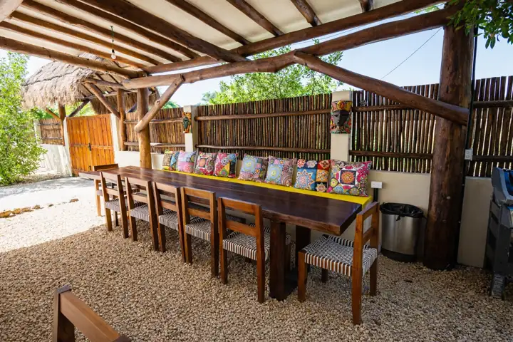 Palapa dining terrace with a long table and embroidered cushions