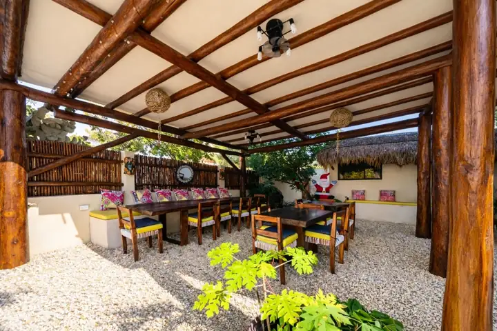 Outdoor dining palapa with a long wooden table for group dinners at Atenea Holbox
