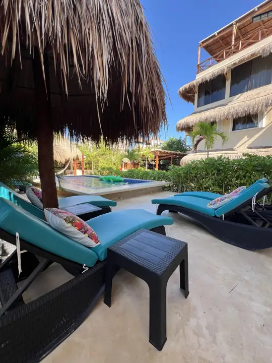 Pool loungers with the two guest buildings and palapas of Atenea Holbox