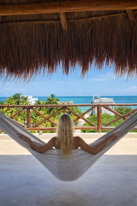 Guest relaxing in a hammock under the rooftop palapa with sea views at Atenea Holbox