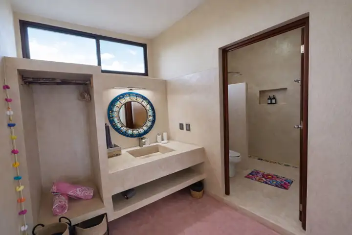 Ensuite bathroom with cement vanity, round mirror and shower room