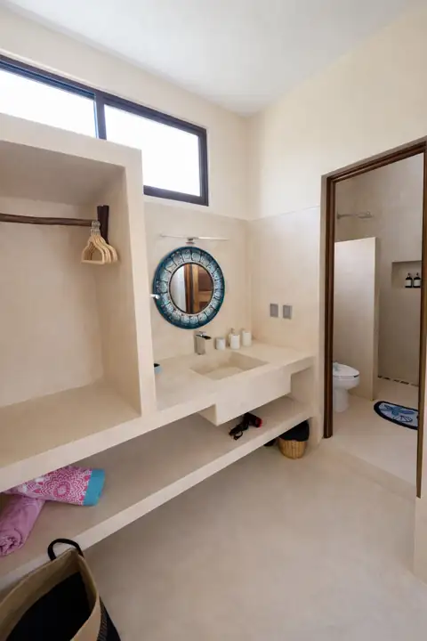 Ensuite bathroom with cement vanity, round mirror and walk-in shower